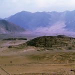 A view across Caral, one of the earliest urban centres in the world and a key study site for research on prehistoric population history, such as reported in this theme issue. This site, 200km north of Lima in Peru, was inhabited roughly between the 29th and 19th centuries BC by the Norte Chico civilization. The mound seen in the centre is the “Edificio Piramidal la Cantera” (the Quarry Pyramidal Building) and the building in the left background is the “Edificio del Altar Circular” or Building of the Circular Altar. Image credit: Daniel Sandweiss.